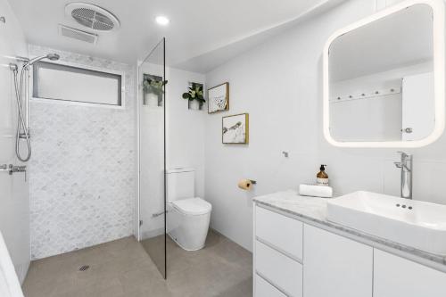 a white bathroom with a shower and a sink at Kirra Views in Gold Coast