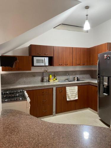 eine Küche mit Holzschränken und einem Kühlschrank aus Edelstahl in der Unterkunft Casa Olguita in Manta