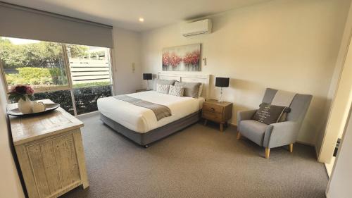 a bedroom with a bed and a chair and a window at Grapevines Boutique Accommodation in Pokolbin