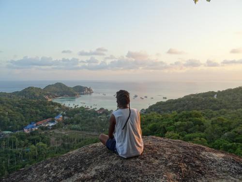 a man sitting on top of a rock looking out at the ocean at Mahoni Guest House in Kelimutu