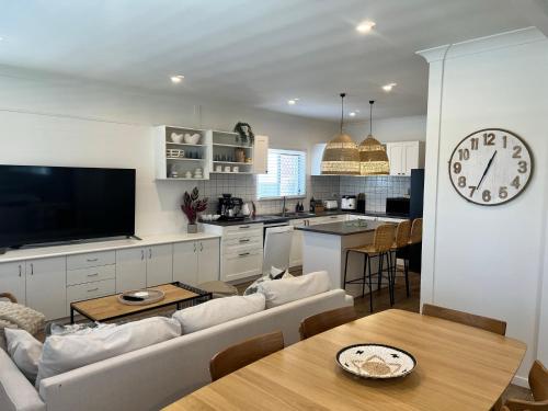 a kitchen and living room with a large clock on the wall at Comfortable Beach Home Scarborough in Scarborough