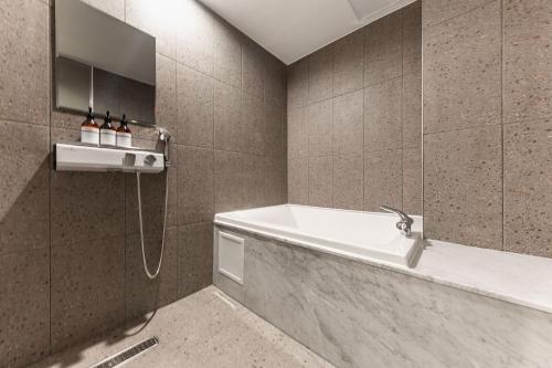 a bathroom with a bath tub and a shower at Brown Dot Hotel Seosan in Seosan