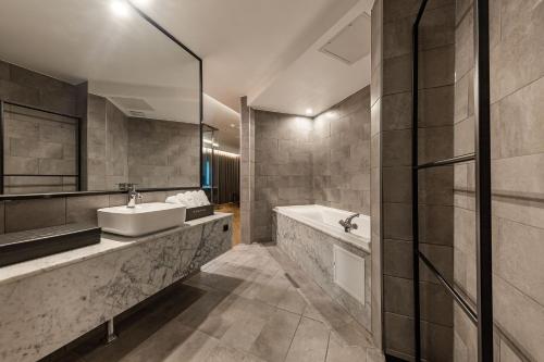 a bathroom with a sink and a tub and a mirror at Brown Dot Hotel Seosan in Seosan