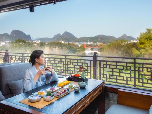 uma mulher sentada numa mesa com comida em Aroma Tea House Former Jing Guan Ming Lou Museum Hotel em Guilin