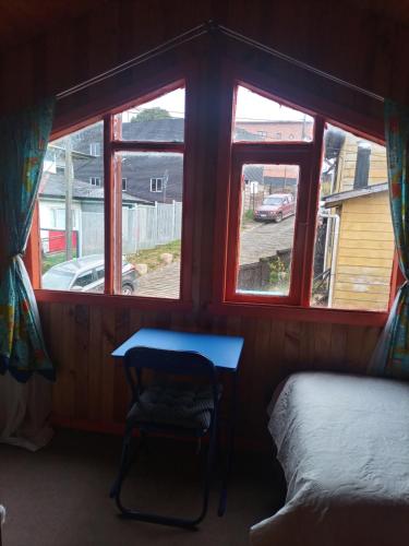 um quarto com uma mesa, uma cama e janelas em Esencia Chilota em Ancud