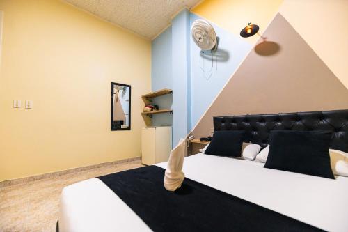 - une chambre avec un grand lit et une tête de lit noire dans l'établissement HOTEL CALLE REAL SUITE, à Medellín