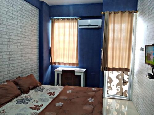 um quarto com paredes azuis e uma cama e um espelho em Vin's Room at Vivo Apartemen em Seturan