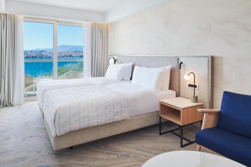 a bedroom with a large bed and a blue chair at Le Meridien Lav Split in Podstrana