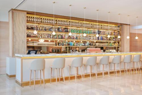 a bar in a restaurant with white stools at Le Meridien Lav Split in Podstrana