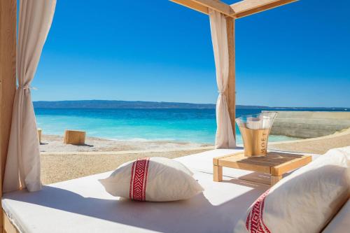 a bed with a view of the beach with a drink on it at Le Meridien Lav Split in Podstrana