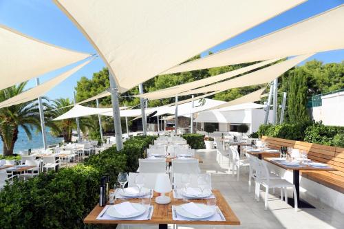 a restaurant with white tables and white umbrellas at Le Meridien Lav Split in Podstrana