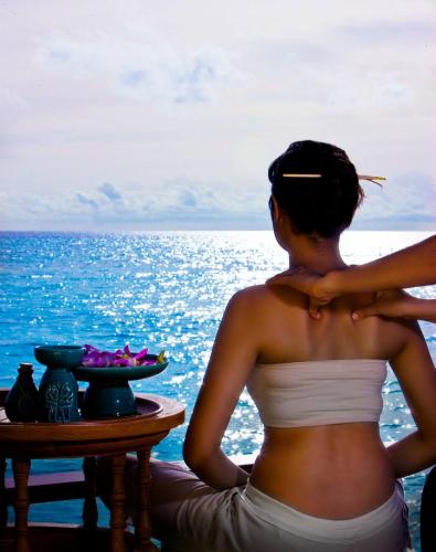 a woman sitting on a table looking at the ocean at Banyan Tree Vabbinfaru in Male City