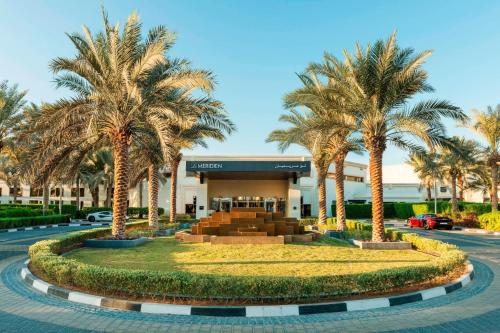 杜拜的住宿－Le Méridien Dubai Hotel & Conference Centre，一座棕榈树度假村,位于一座建筑前