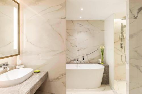 a white bathroom with a sink and a mirror at Le Méridien Dubai Hotel & Conference Centre in Dubai