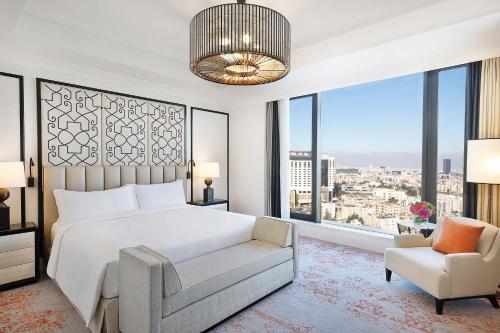 a bedroom with a bed and a chair and windows at The St. Regis Amman in Amman