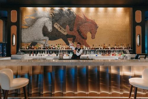 a man standing behind a bar with horses on the wall at The St. Regis Amman in Amman