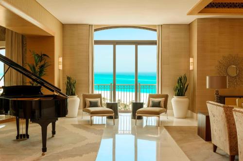 a living room with a piano and a view of the ocean at The St. Regis Saadiyat Island Resort, Abu Dhabi in Abu Dhabi