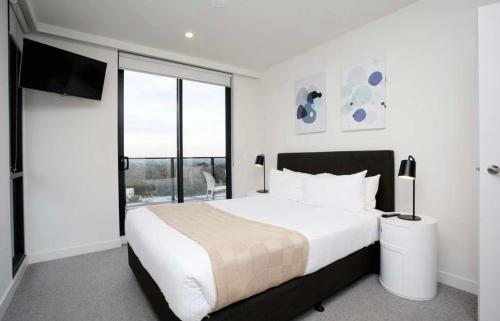 1 dormitorio con 1 cama grande y TV en Bright Bundoora Apartments, en Melbourne