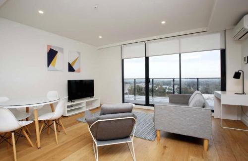 sala de estar con mesa, sillas y TV en Bright Bundoora Apartments, en Melbourne
