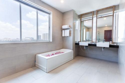 a bathroom with a tub and two sinks and a large window at Joli Hotel in Phnom Penh