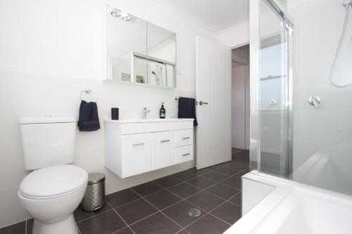 a white bathroom with a toilet and a shower at Stay in Mudgee in Mudgee