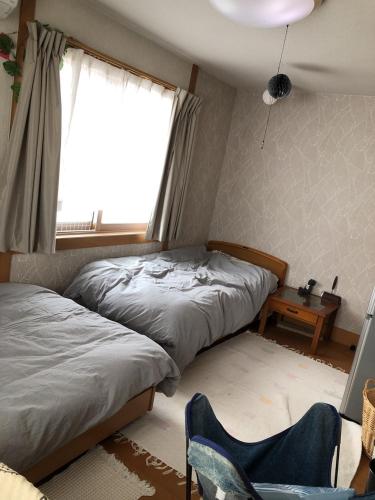 a bedroom with two beds and a chair and a window at 男性のみでの利用不可ーペット連れ歓迎 女性連れ専用ーotomari MUSUHIータイ古式マッサージや妊産婦ケアが受けられる 源泉掛け流し温泉側の宿 ドッグラン可 in Takamatsu