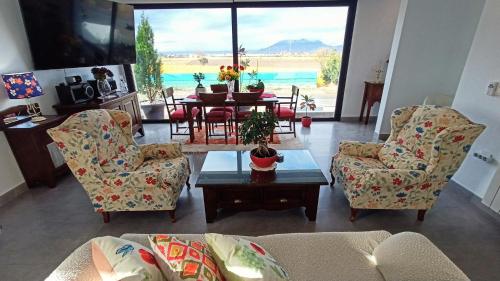 a living room with a couch and chairs and a table at Chalet con piscina y jardín, no fumadores ni fiestas in Cúllar-Vega