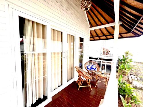 un porche de una casa con mesa y sillas en The KUBU 221 en Lembongan