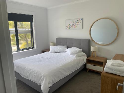 a bedroom with a large bed and a mirror at Little White House on Ecclestone, Riverside in Alanvale
