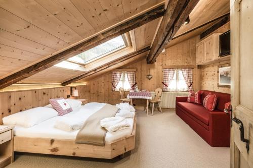 a bedroom with a large bed and a red couch at Hotel Oberraindlhof in Senales