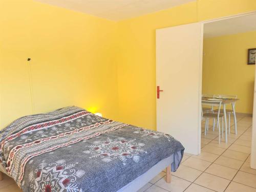 - une chambre avec un lit, une table et des murs jaunes dans l'établissement Appartement lumineux 2 pièces, 4 couchages, proche commodités, Cap d'Agde - FR-1-249-378, au Cap d'Agde
