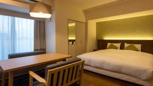 a bedroom with a bed and a desk and a table at Hotel Global View Hakodate in Hakodate