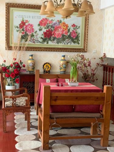a dining room with a table and a painting of flowers at Mama Naxi Guesthouse in Lijiang