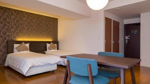 a bedroom with two beds and a table and chairs at Hotel Global View Hakodate in Hakodate