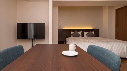 a room with a table and chairs and a bed at Hotel Global View Hakodate in Hakodate