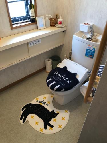 a bathroom with a black cat rug next to a toilet at ペット連れ歓迎 女性連れ専用ーotomari MUSUHIータイ古式マッサージや妊産婦ケアが受けられる 源泉掛け流し温泉側の宿 ドッグラン可 in Takamatsu