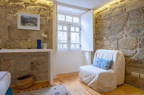 a room with a stone wall with a chair and a window at PWHC Miragaia Apartments in Porto