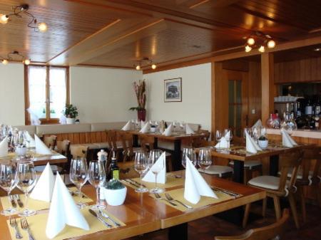 ルツェルンにあるHotel Ristorante Schlössliの木製テーブルと椅子(白いナプキン付)のあるレストラン