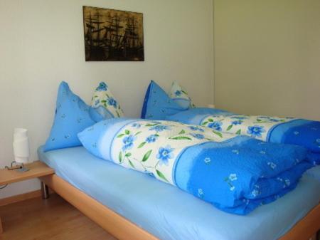 ein Bett mit blauer Bettwäsche und Kissen darauf in der Unterkunft Hotel Ristorante Schlössli in Luzern