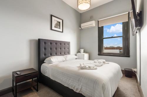 a bedroom with a bed with white sheets and a window at The Great Western Hotel in Orange
