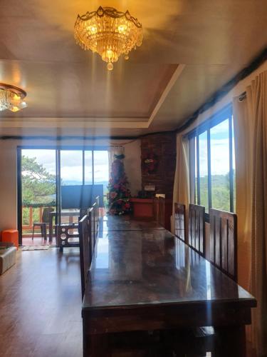 ein Esszimmer mit einem langen Tisch und einem Kronleuchter in der Unterkunft The 3rd Floor Lot 16 Country Estates inside Camp John Hay- with view in Baguio City