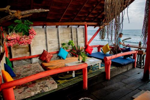 a porch with a bed and chairs on the beach at Brother's Beach Home in Galle