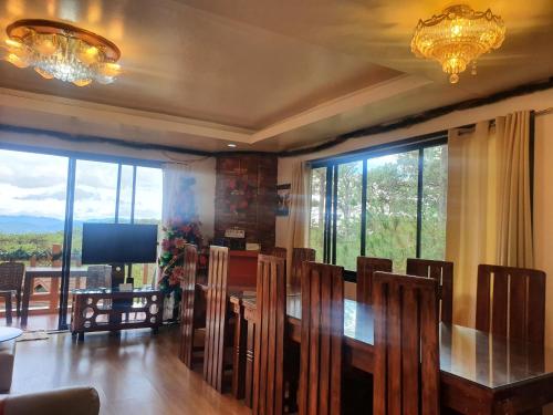 ein Esszimmer mit einem Tisch, Stühlen und einem TV in der Unterkunft The 3rd Floor Lot 16 Country Estates inside Camp John Hay- with view in Baguio City