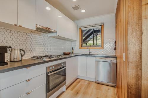 a kitchen with white cabinets and stainless steel appliances at Fountains 3 in Mount Hotham
