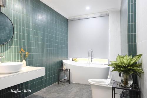 La salle de bains est pourvue de carrelage vert, d'une baignoire et d'un lavabo. dans l'établissement Villa Mayfair B101 Đại Lải - 5 Phòng ngủ, à Thanh Cao
