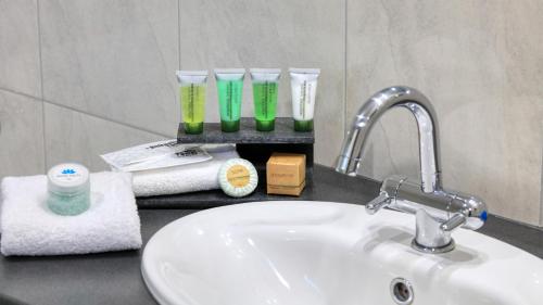 a bathroom counter with a sink and some glasses on it at Glider City Motel Benalla in Benalla