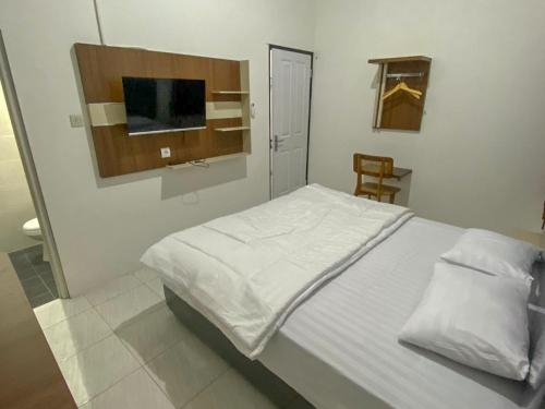 a bedroom with a white bed and a television at Nikie Guesthouse in Semarang