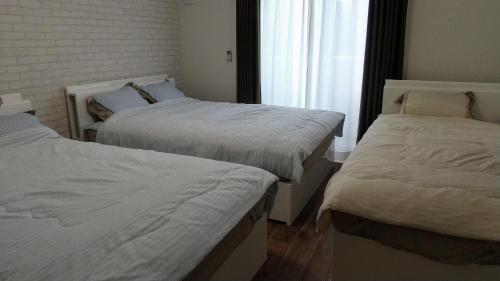 2 camas en una habitación con ventana en メゾネットHIRAKU en Izumi-Sano