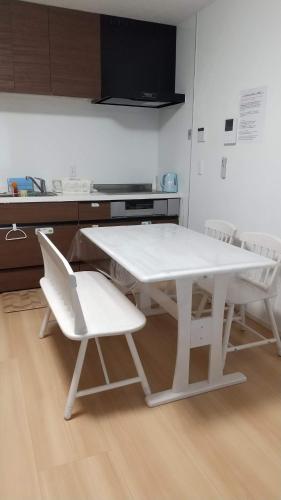 メゾネットHIRAKU في إيزوميسانو: طاولة بيضاء وكرسيين بيض في مطبخ