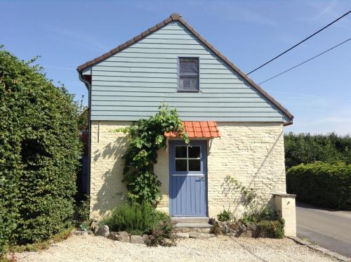 una pequeña casa de ladrillo blanco con puerta azul en Gîte les Mineurs, en Zottegem